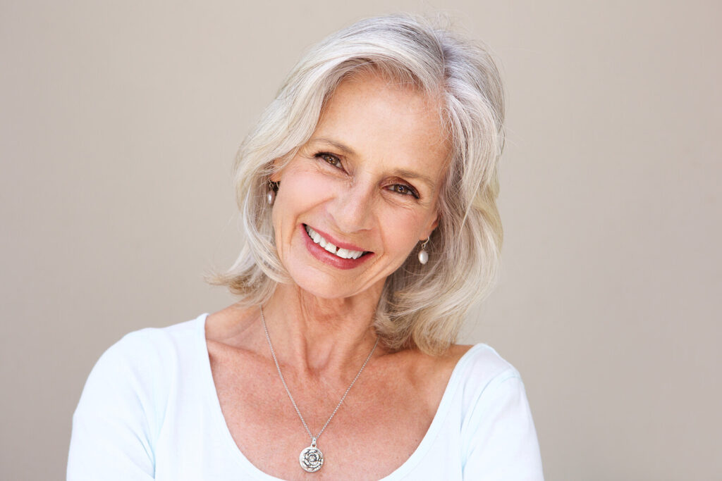 Image of an older woman with white hair smiling. If you are dealing with the transition of menopause, work with a supportive holistic therapist in life changes therapy in Hermosa Beach, CA.