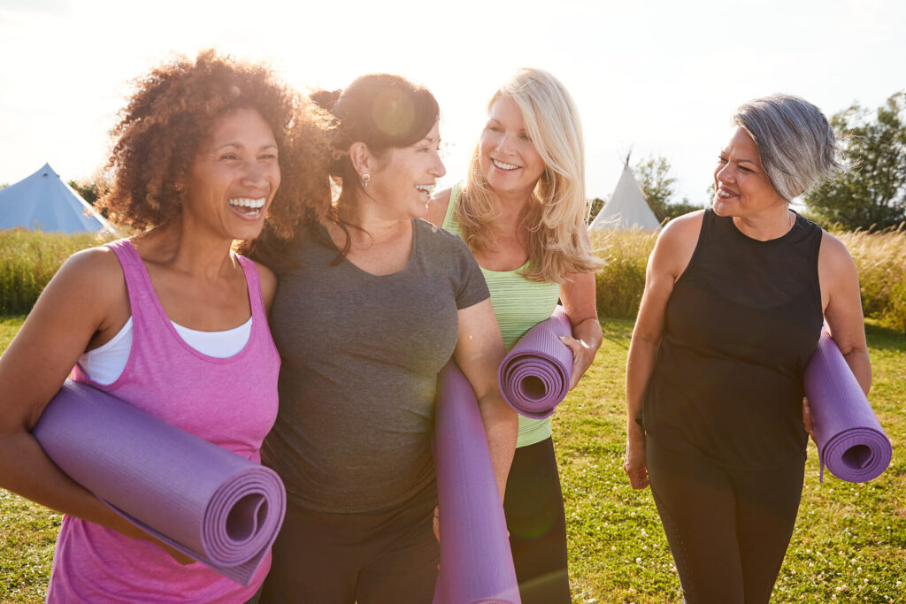 Image of a group of smiling woman holding yoga mats. If you are dealing with a major life change, work with a skilled life transition therapist in Hermosa Beach, CA to overcome the challenges. 