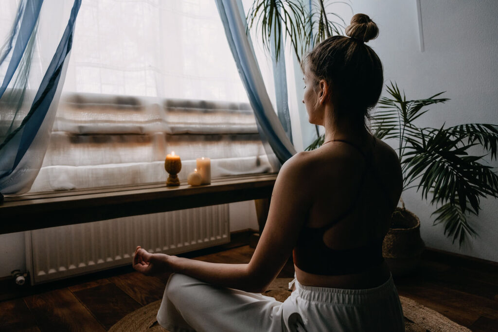 Image of a woman sitting on the ground practicing yoga. This image represents how holistic techniques such as yoga can help you cope with your symptoms. Learn how anxiety therapy in Hermosa Beach, CA can help.