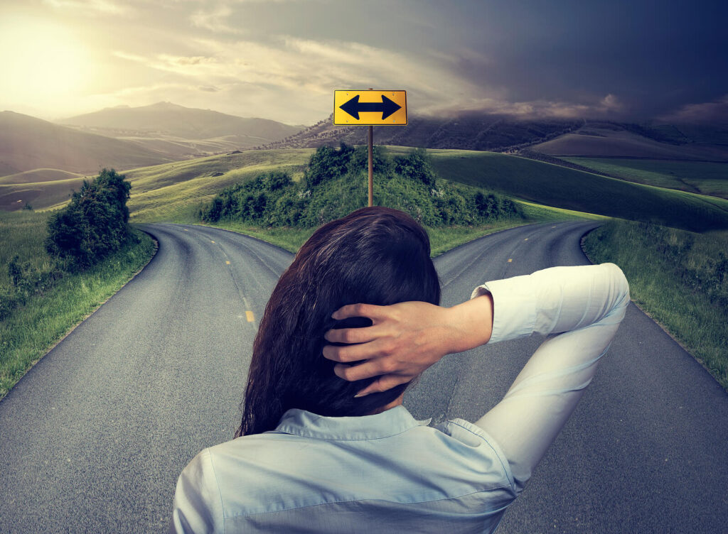 Image of a woman looking between two roads. This image represents a major life change and the difficult decisions needed to be made to embrace them. Find support with life transition therapy in Hermosa Beach, CA.