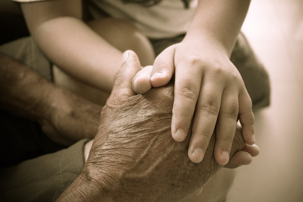 Image of an older person holding hands with a child. Learn to effectively communicate with your family as you balance your aging parents and family life. Work with a skilled life transition therapist in Manhattan Beach, CA.