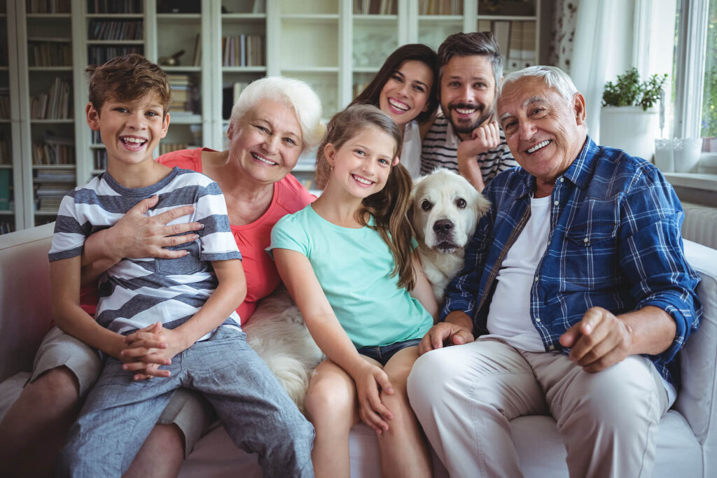 Image of a smiling generational family sitting on a couch. Find a balanced life where you feel supported in helping your family and parents with life changes therapy in Manhattan Beach, CA.