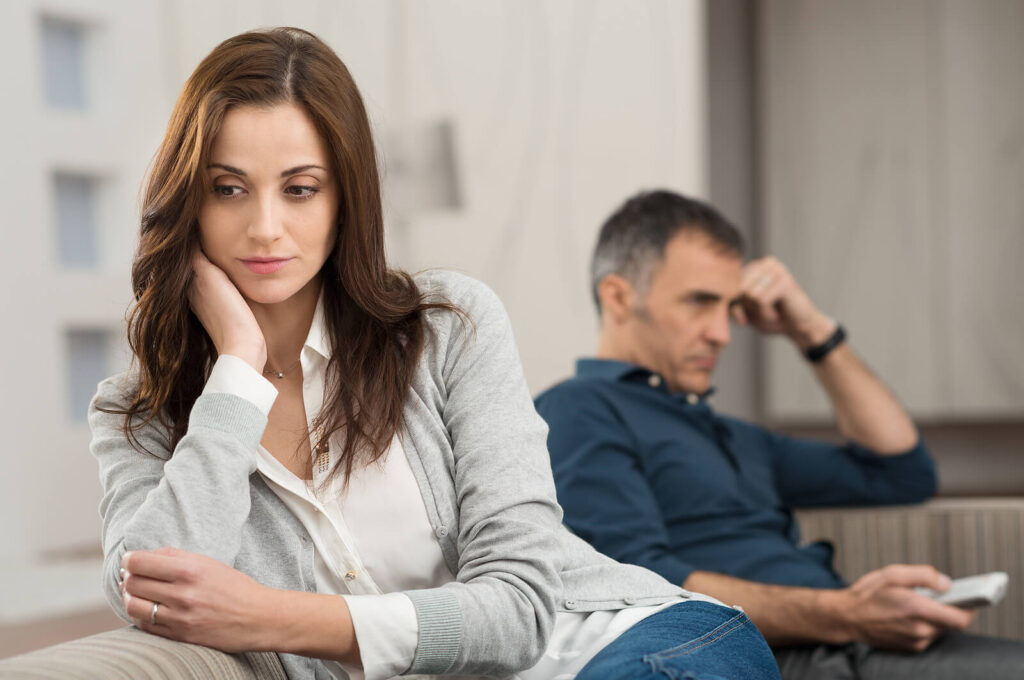 Image of an upset woman facing away from her male partner on the couch. If you are going through a divorce, discover how life changes therapy in Manhattan Beach, CA can help you begin coping with change.