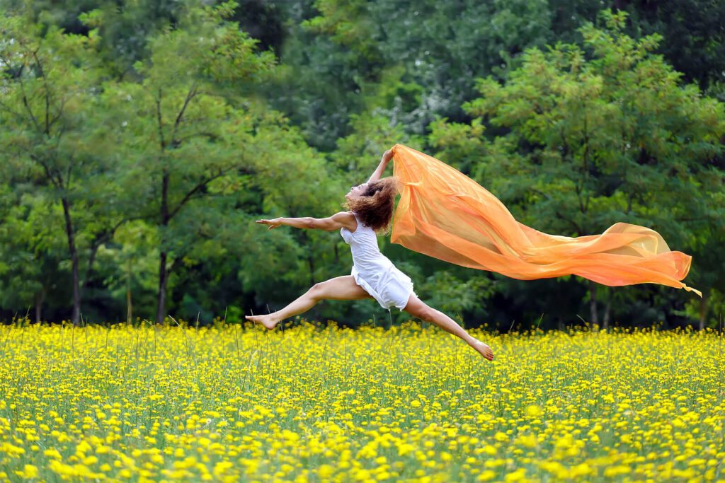 Image of a woman running and jumping through a field of flowers. Begin holistic healing for anxiety with the help of anxiety therapy in Manhattan Beach, CA.