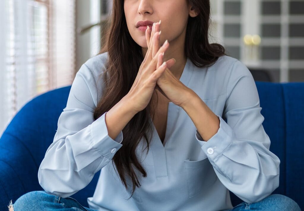 Image of an anxious woman sitting with her hands clasped. Discover how a skilled anxiety therapist in Manhattan Beach, CA can help you begin coping with your anxiety symptoms in healthy ways.